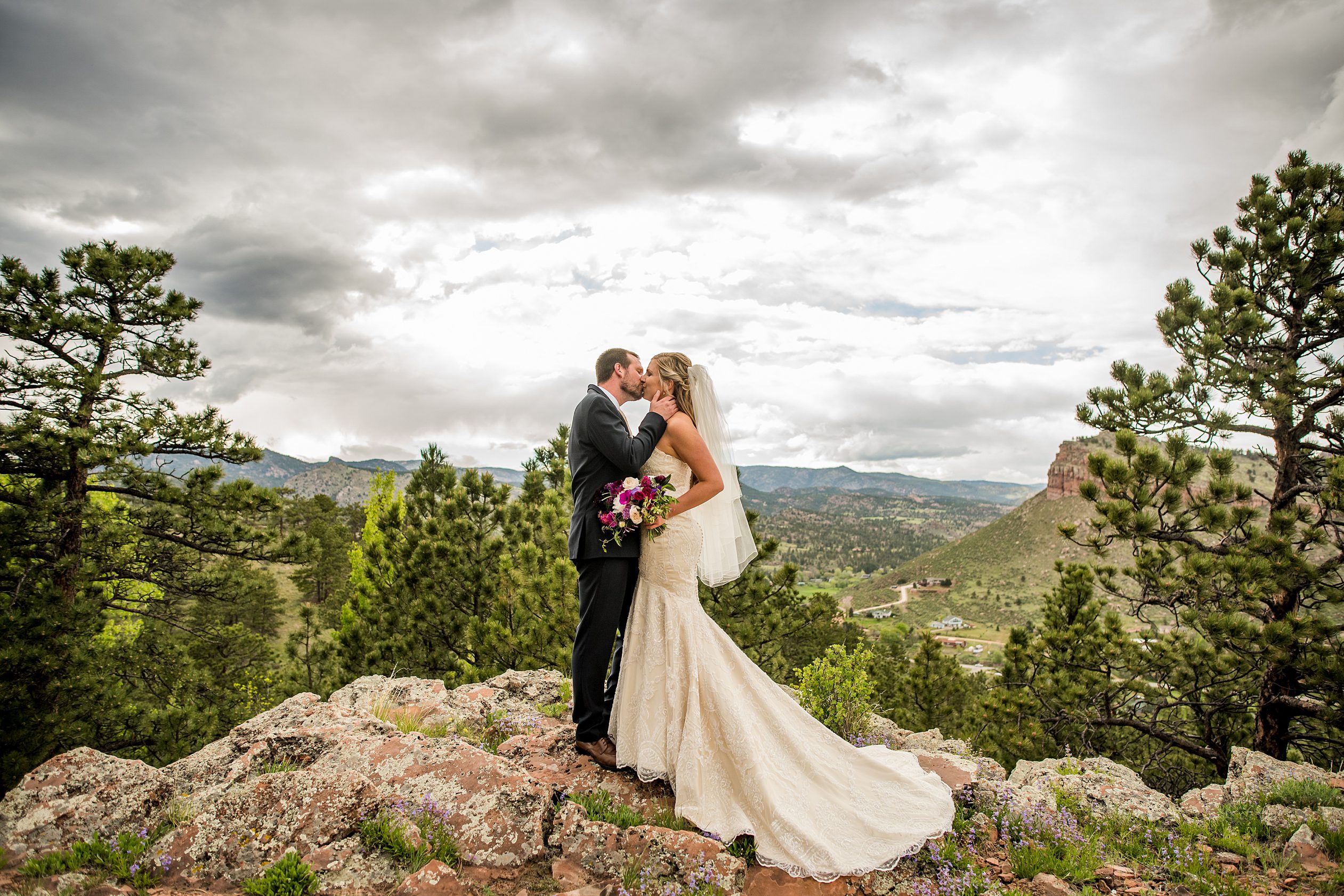 bride and groom kiss on the top of a mountain in Colorado