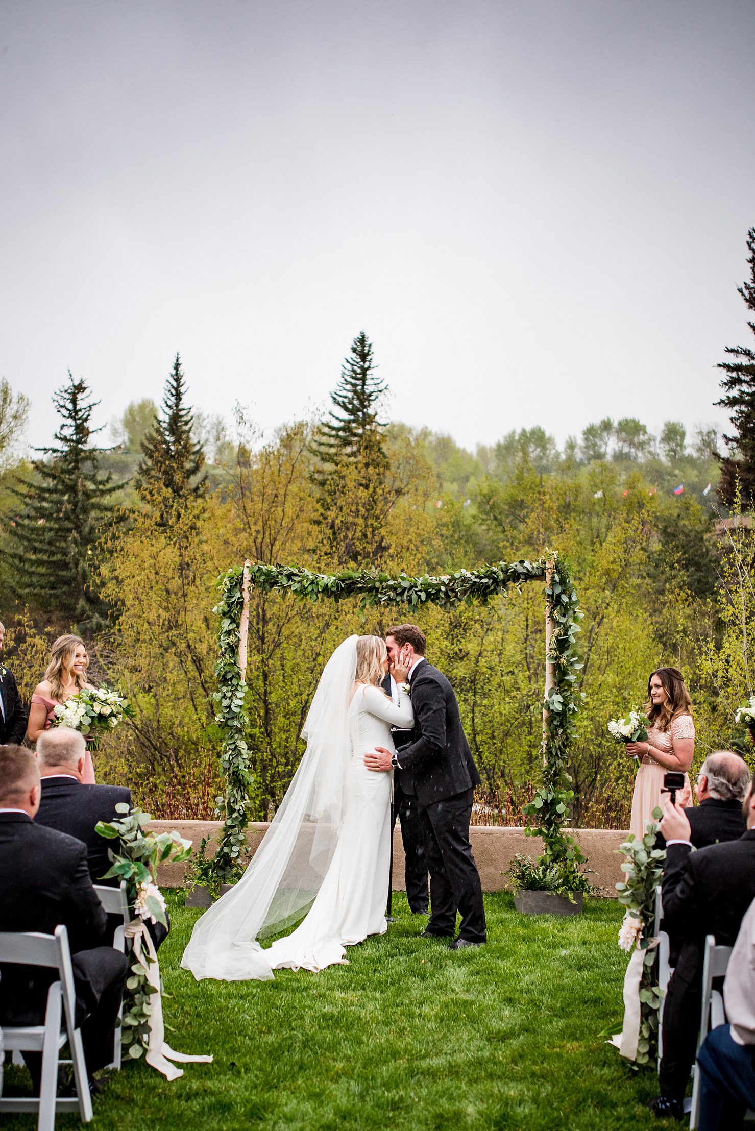 bride and groom have their first kiss in the rain