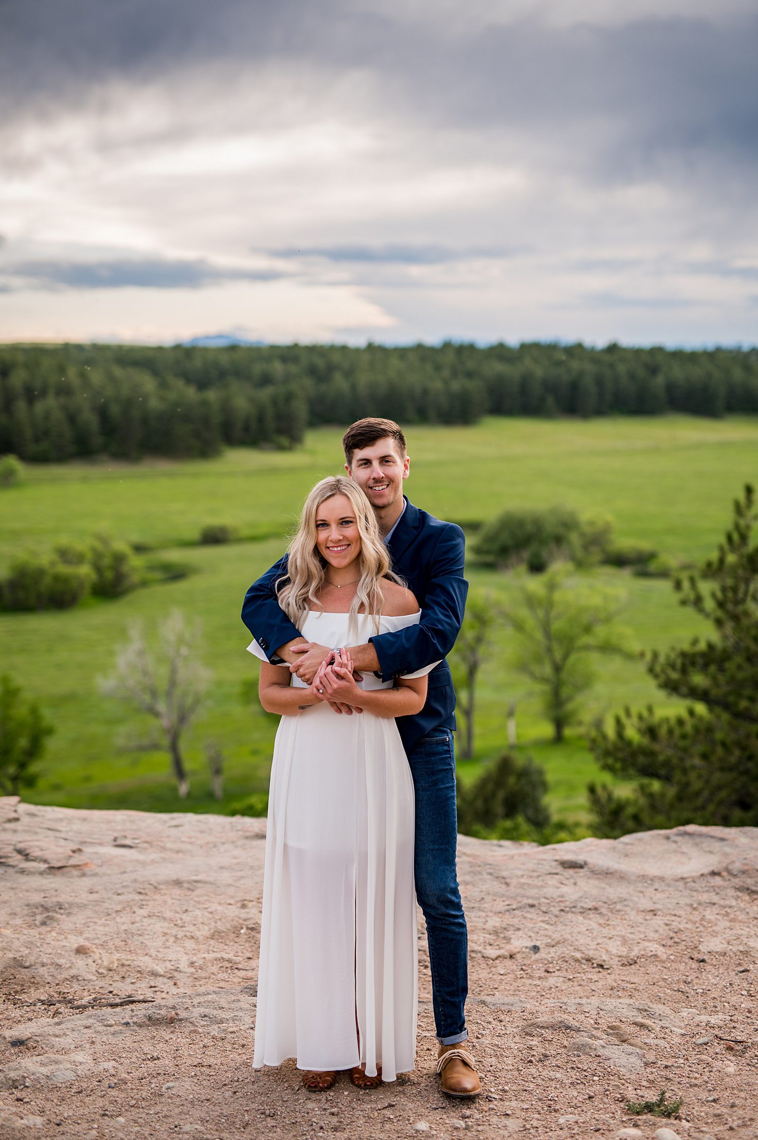 engaged couple hugging with field behind them in Colorado