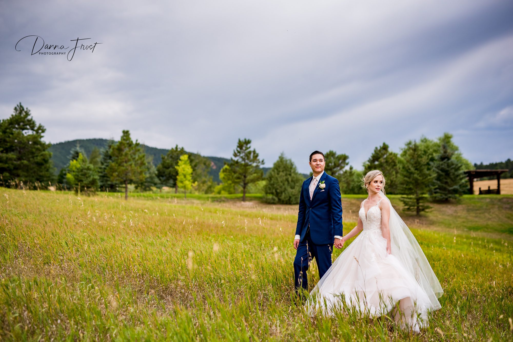 bride and groom in field with rain clouds