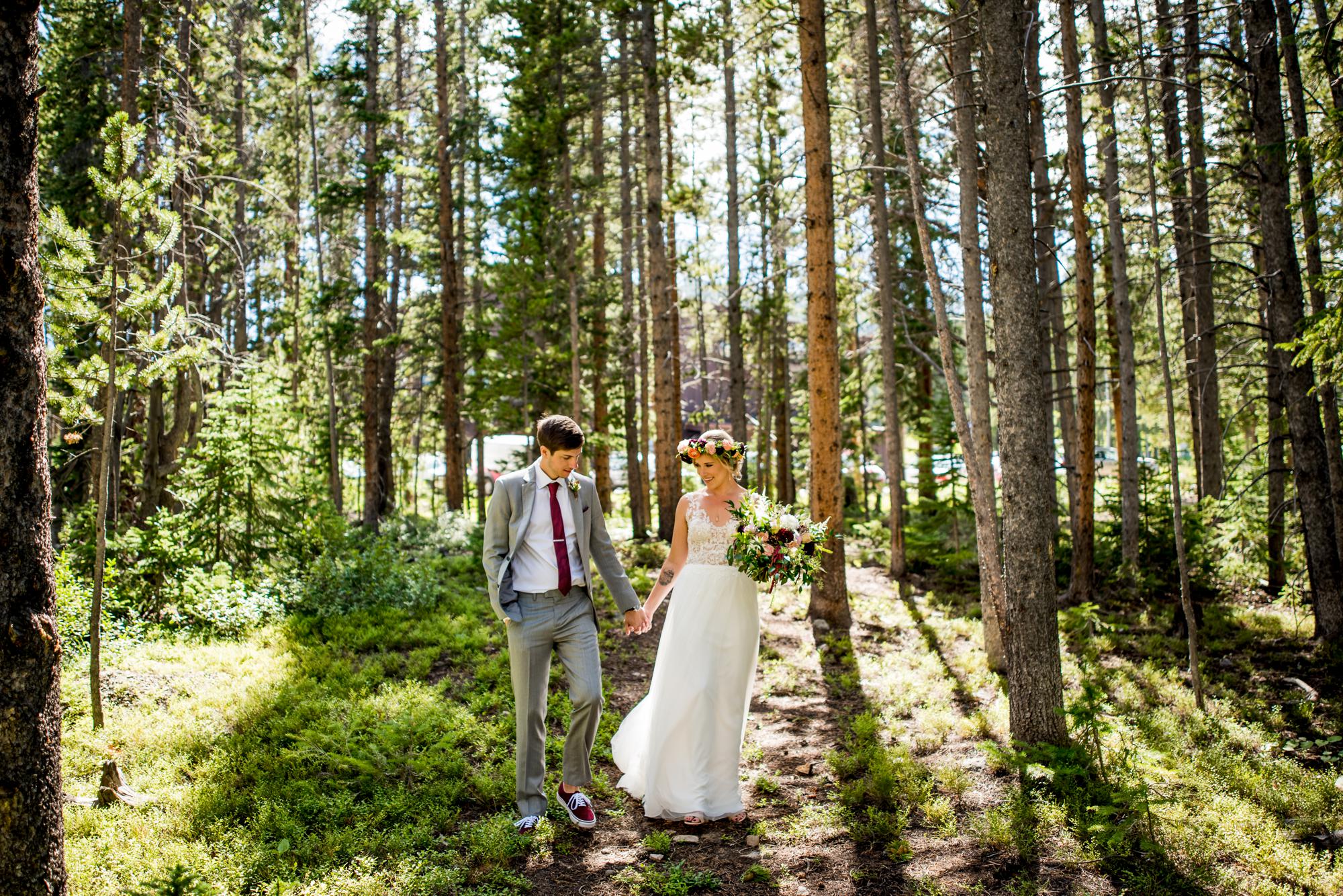 bride and groom walking through the tall Colorado trees at Ten Mile Station