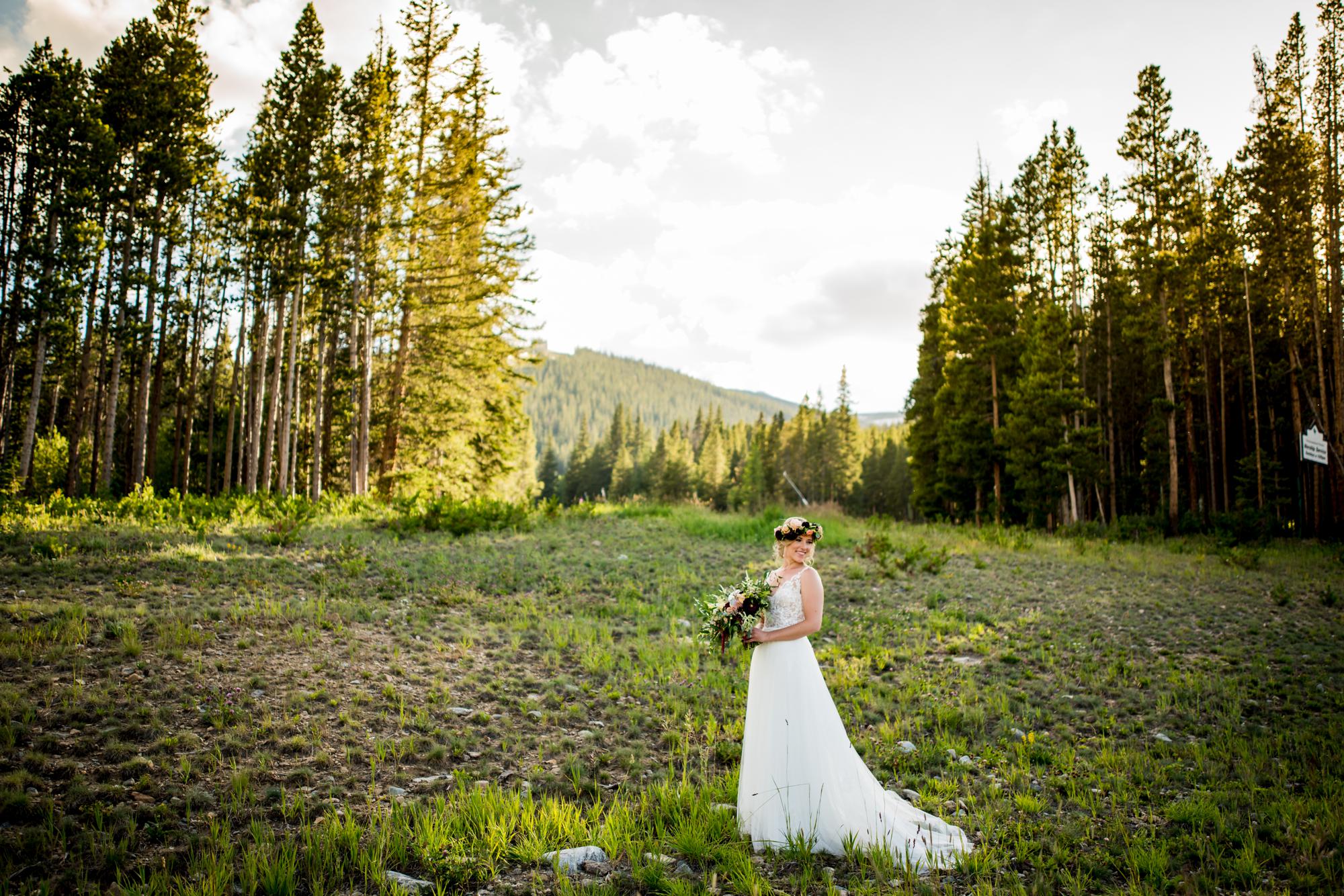 stunning Boho bride in a Colorado field with the mountains and trees in the background 
