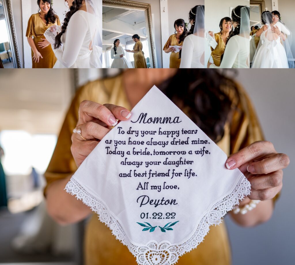 A Denver bride lovingly hands her mother a delicate embroidered hanky as a gift, capturing a heartfelt moment between them. The mother smiles through happy tears, holding the handkerchief as a treasured keepsake, while the bride looks on with warmth and affection on her wedding day.