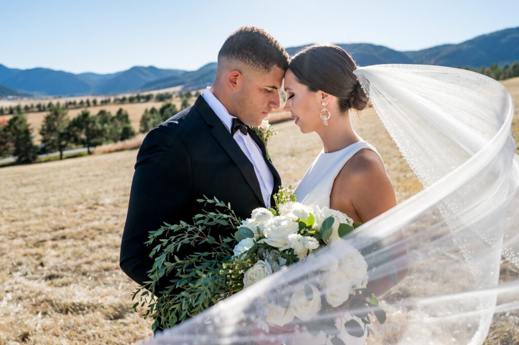 wedding couple in Colorado stand together romantically as the brides veil blows in the wind at spruce mountain ranch.