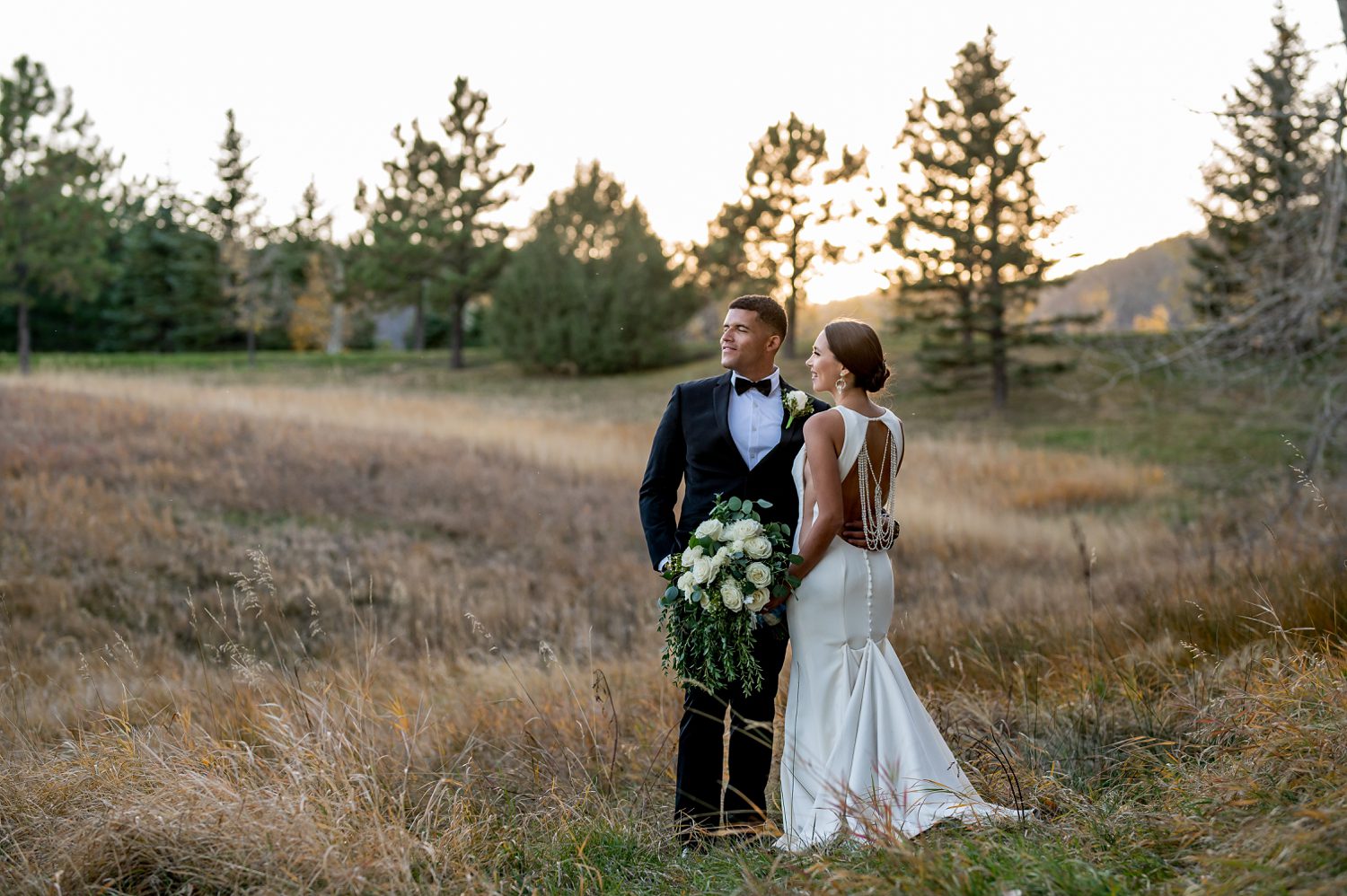 bride and groom outside of spruce mountain ranch in Colorado. Wedding couple taking romantic wedding photos during golden hour sunset.
