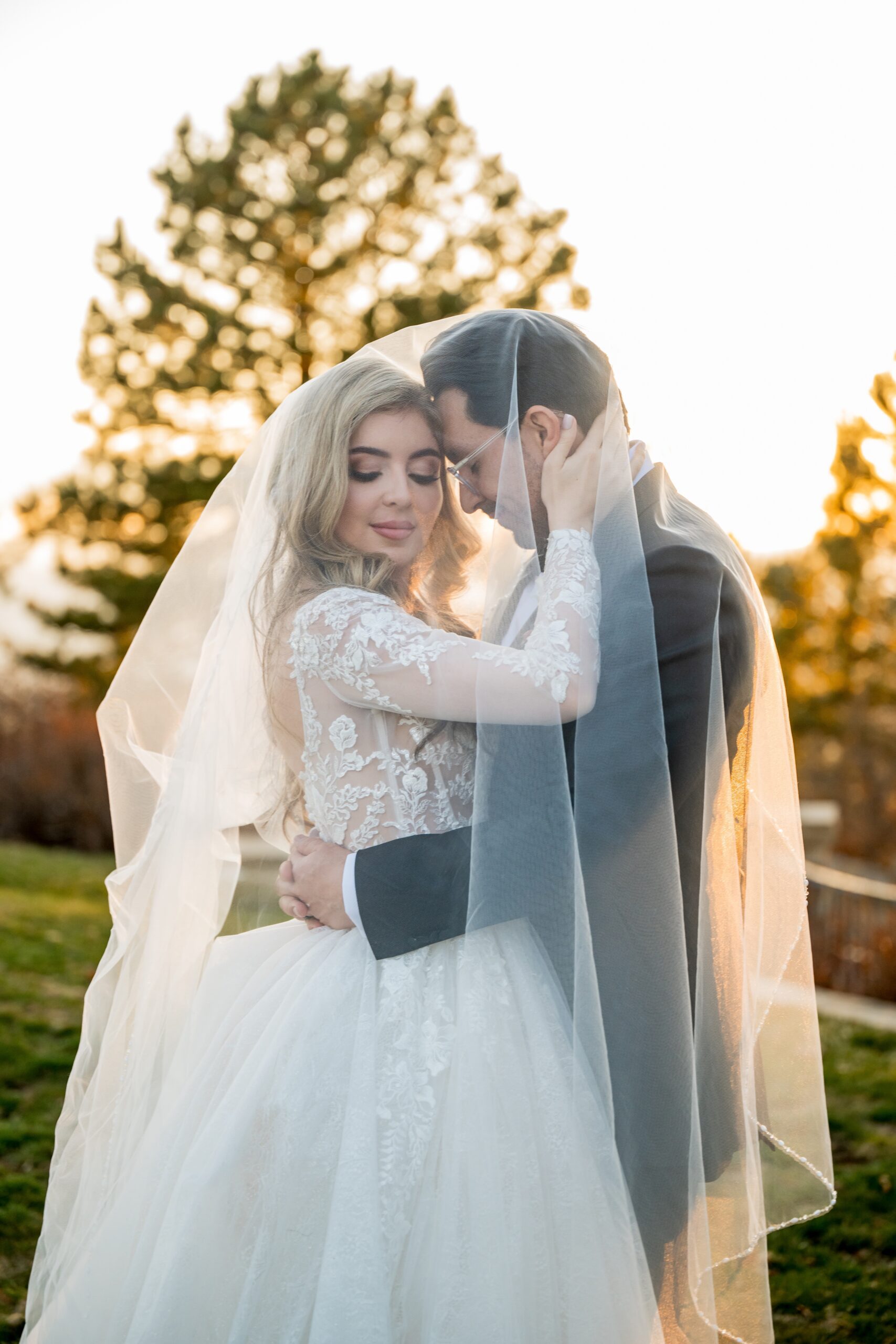 bride and groom under the brides veil during sunset at The Sanctuary Golf Course